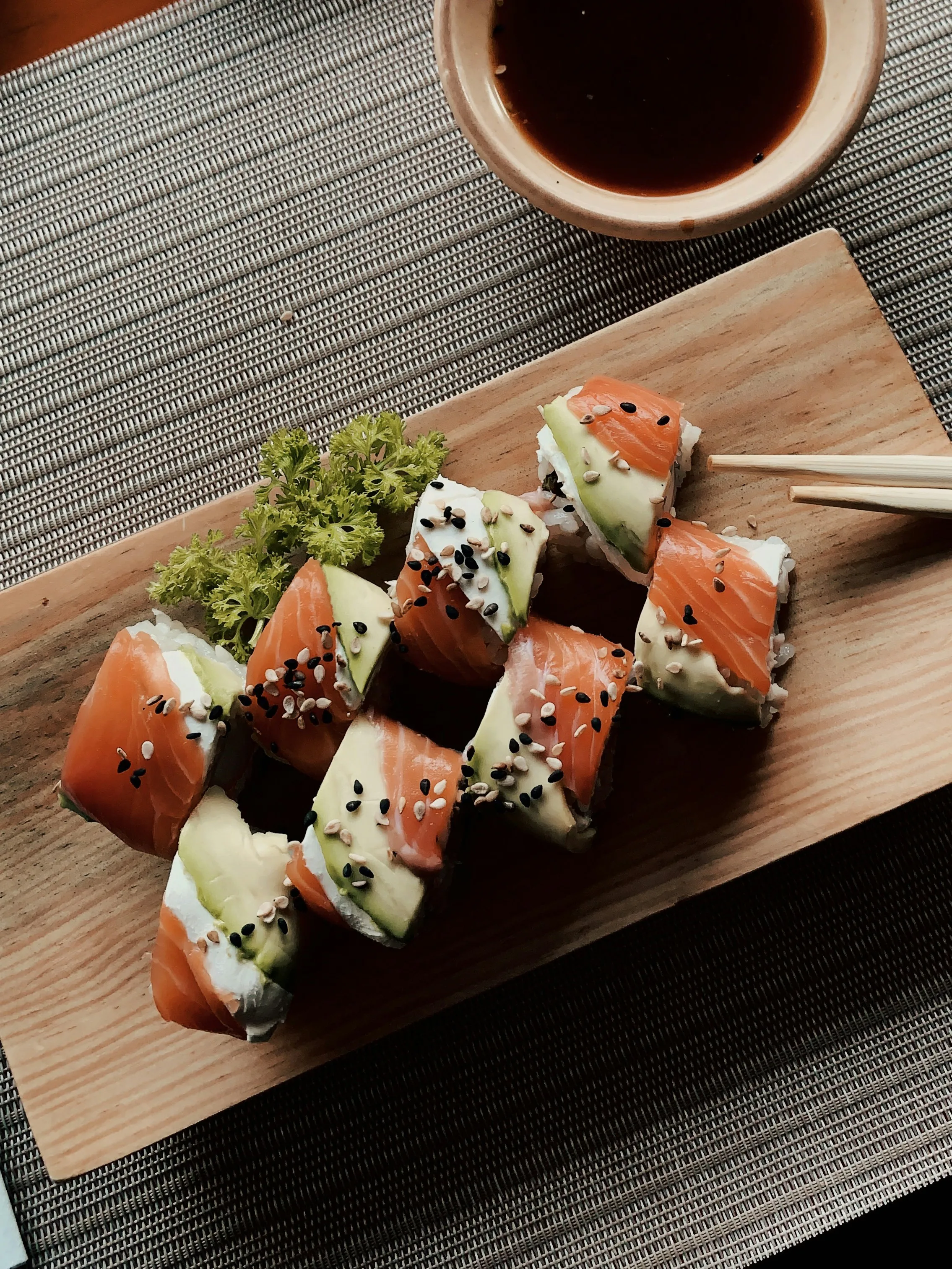 Fresh salmon avocado sushi rolls on wooden board with soy sauce at Golden Dragon Restaurant, a Chinese Restaurant in East Troy